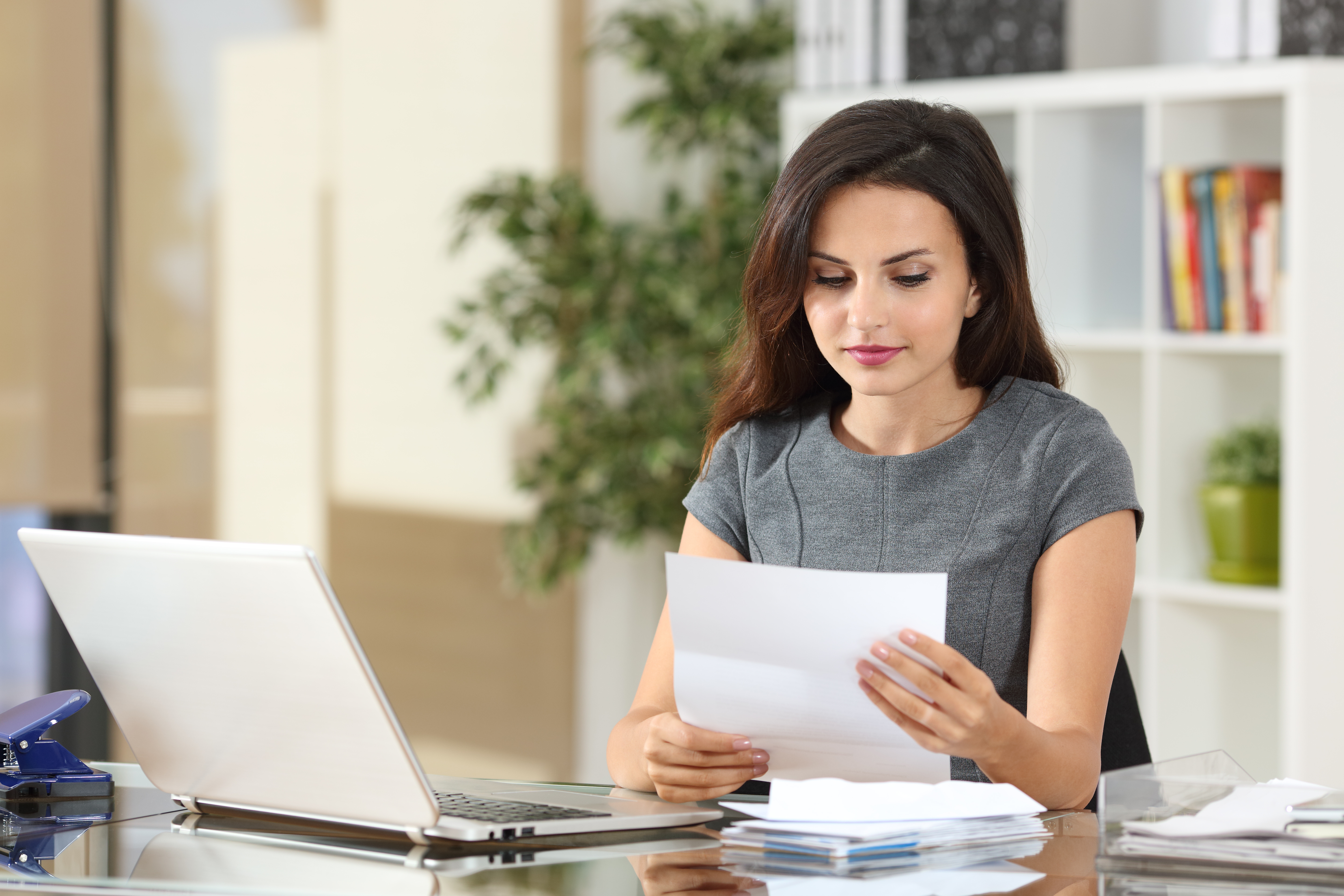 Portrait of a woman working at office reading a letter in a desktop