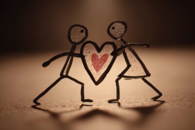 Two stick figures hold a heart symbolizing support