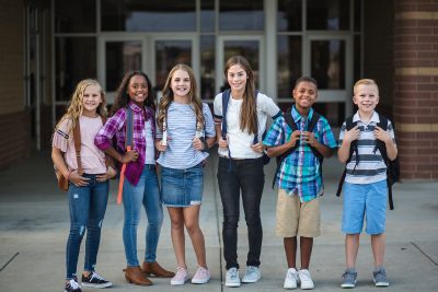 Large Group portrait of pre-adolescent school kids smiling in front of school