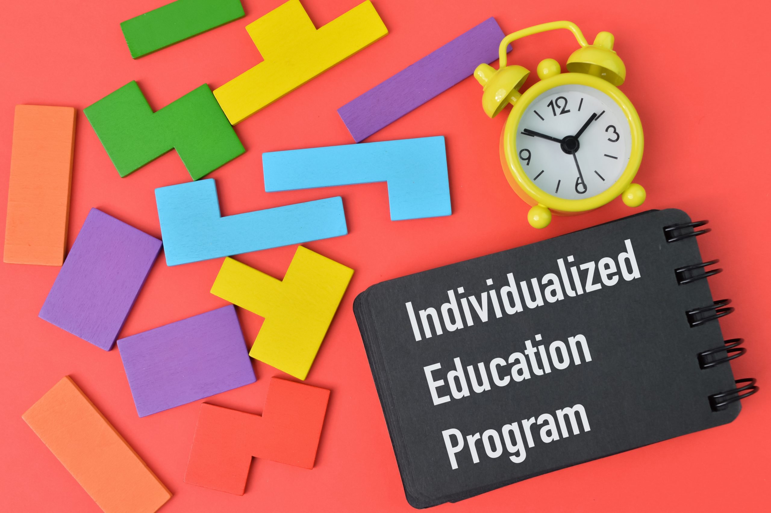 Colorful wooden blocks, clock and notebook written with INDIVIDUALIZED EDUCATION PROGRAM