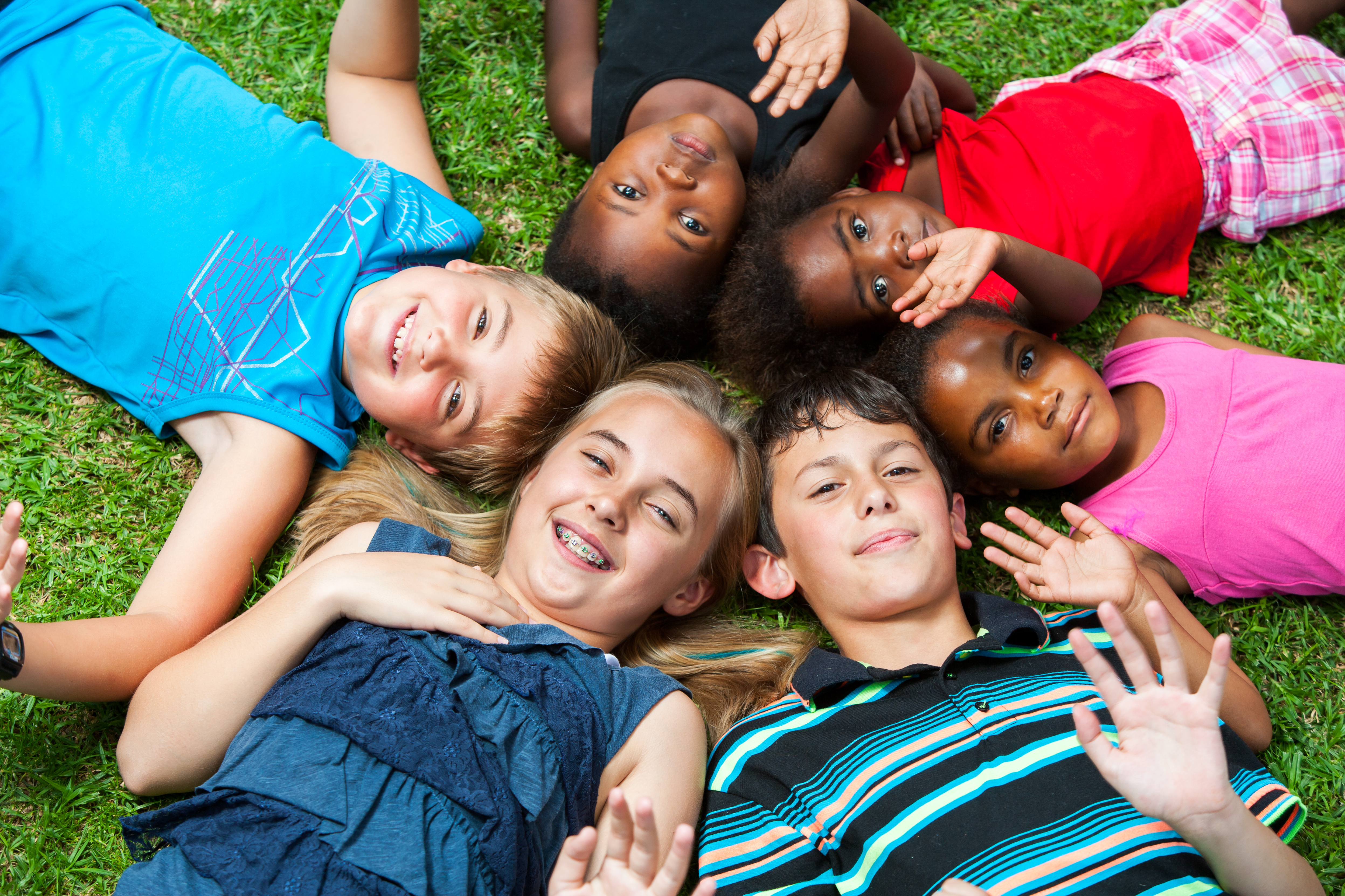 Diverse multiracial group of kids laying together joining heads together in a circle