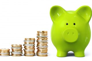 A green piggy bank is at one side with stacks of coins at the other side