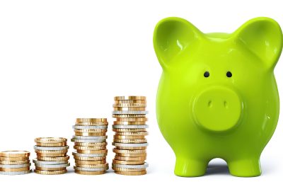 A green piggy bank is at one side with stacks of coins at the other side