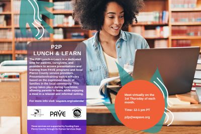 image shows a young woman sitting at a table in a library on a laptop, smiling.